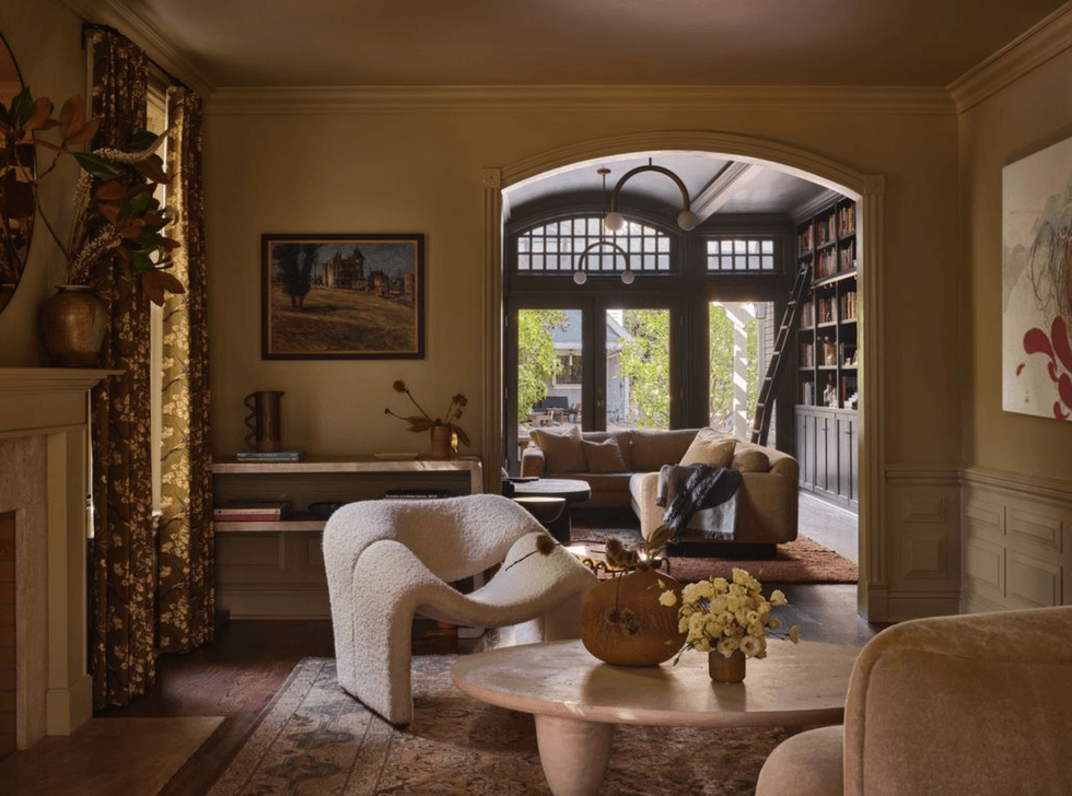 Cozy living room with arched doorway, plush chairs, and bookshelves.