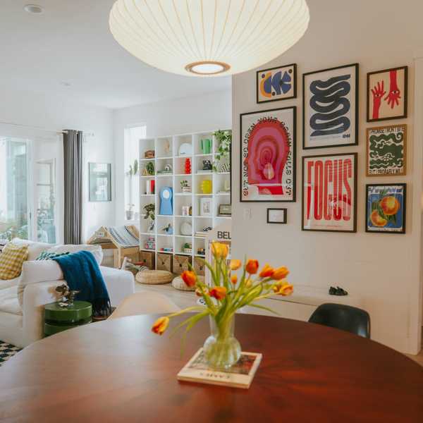 Cozy living room with colorful art, white shelves, and tulips on a round table.