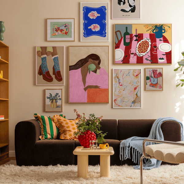 Cozy living room with colorful artwork, dark sofa, and light wooden table on a fluffy rug.