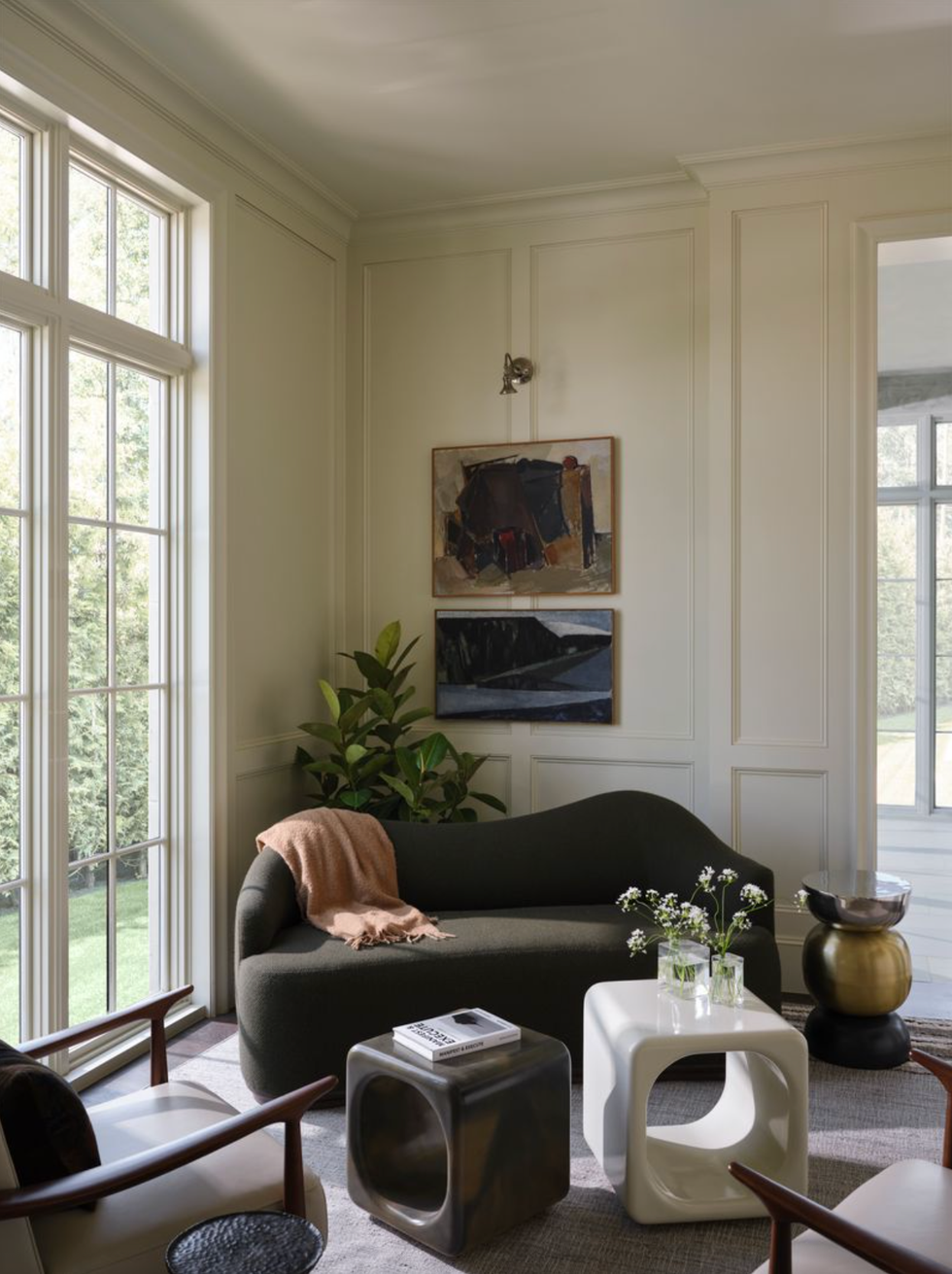 Cozy living room with dark sofa, abstract art, and large windows.