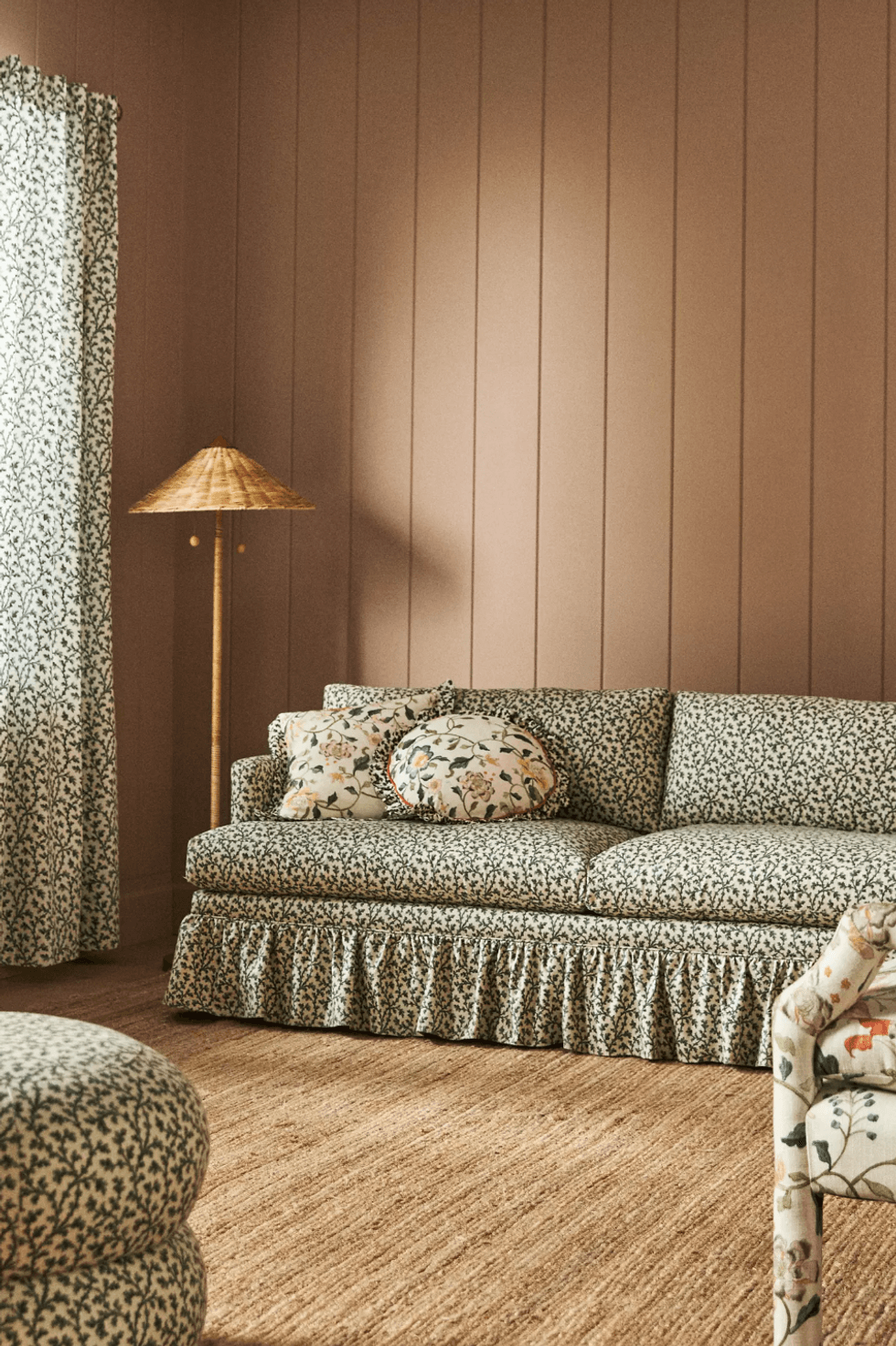 Cozy living room with floral sofa, wicker lamp, and patterned curtains.
