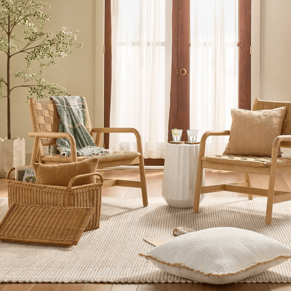Cozy living room with light wooden chairs, soft cushions, and a small white side table.