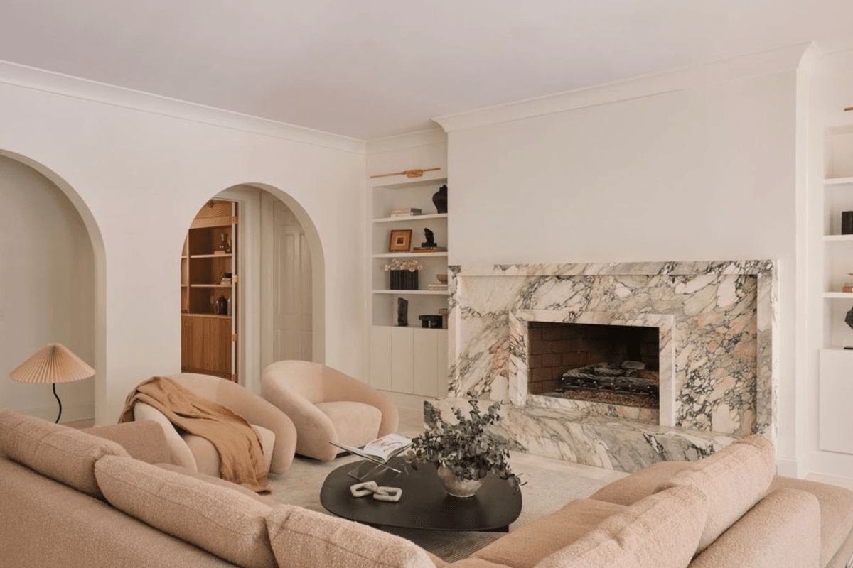 Cozy living room with marble fireplace, soft seating, and modern decor.