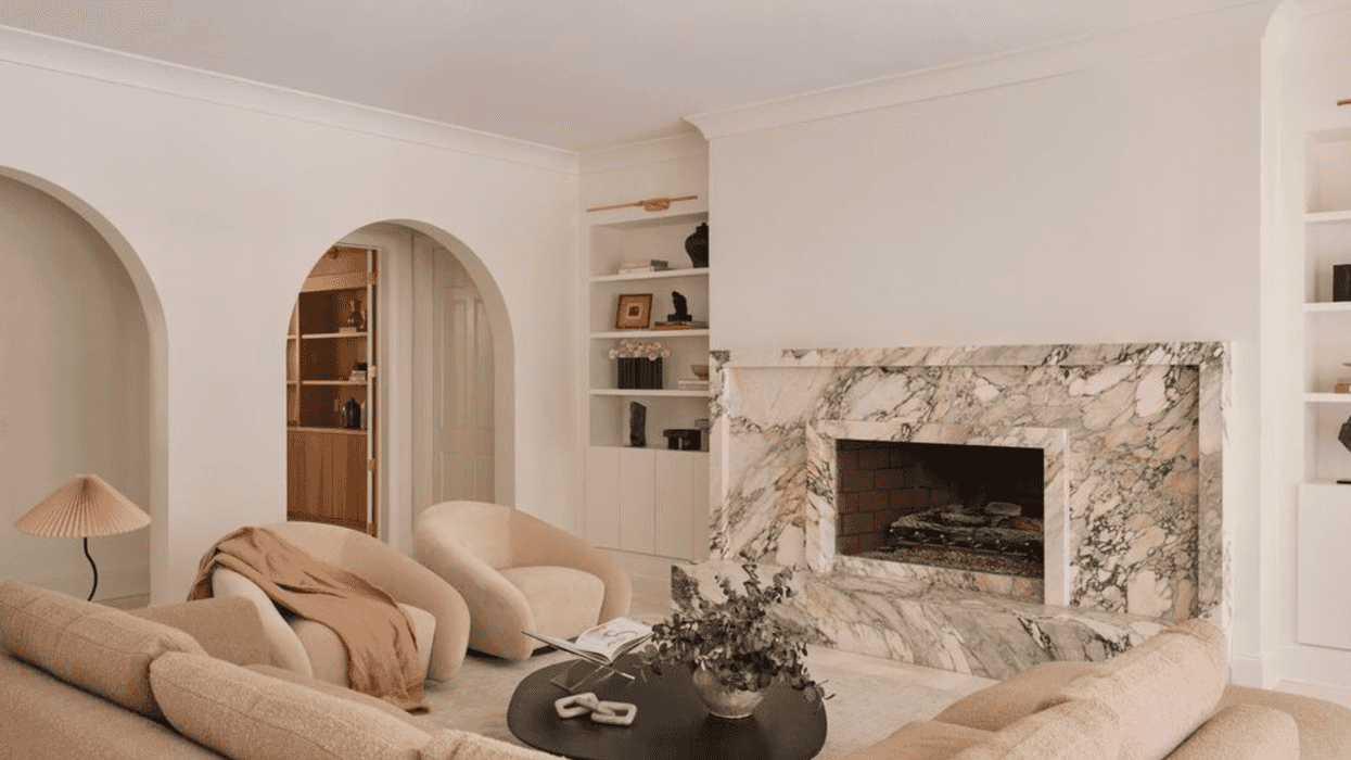 Cozy living room with marble fireplace, soft seating, and modern decor.