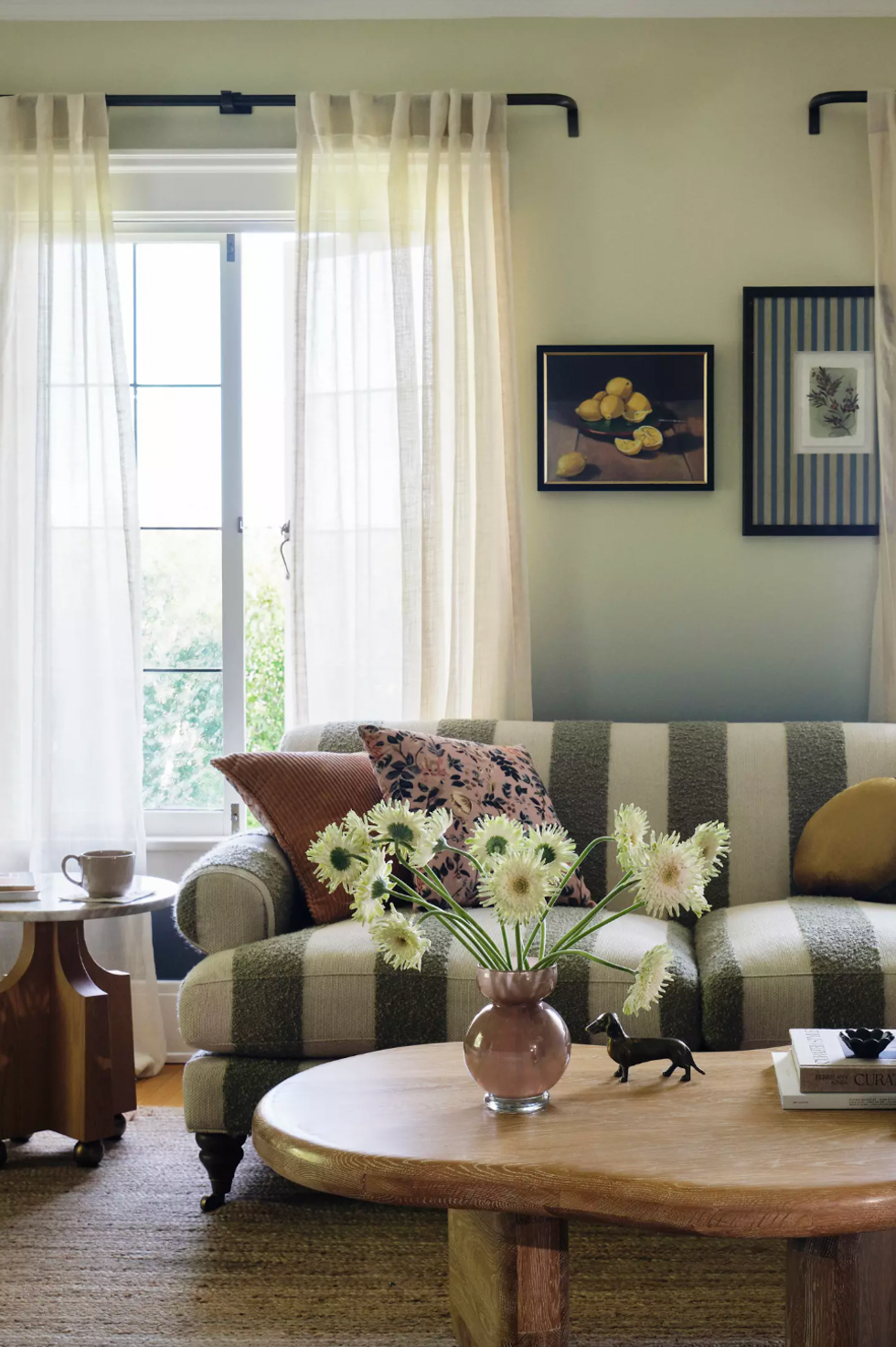 Cozy living room with striped sofa, floral cushions, and flowers on a wooden coffee table.