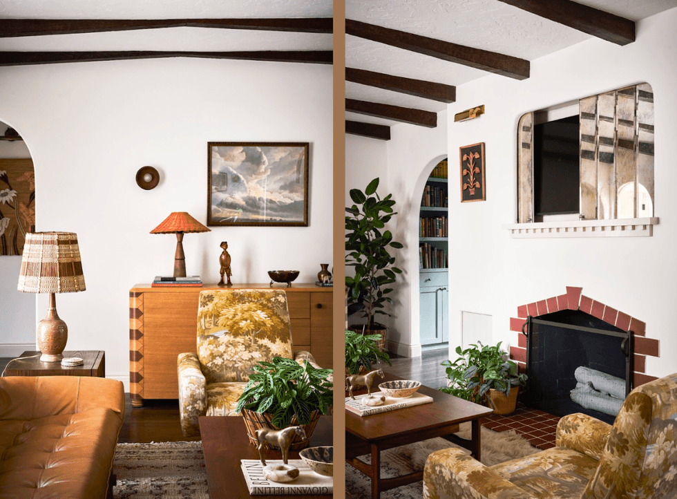 Cozy living room with vintage decor, plants, beamed ceiling, and a fireplace.