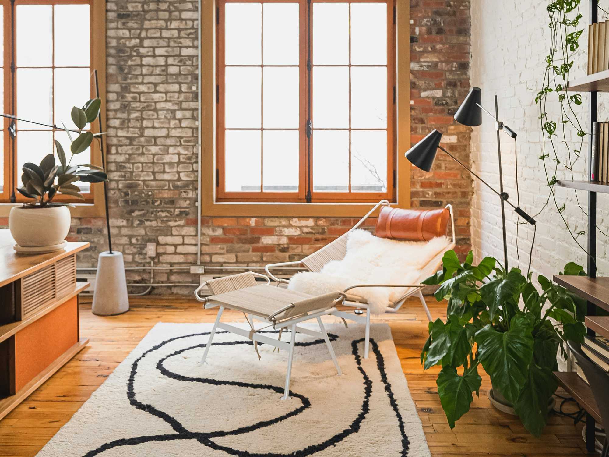 Cozy living space with a lounge chair, plants, and large windows.