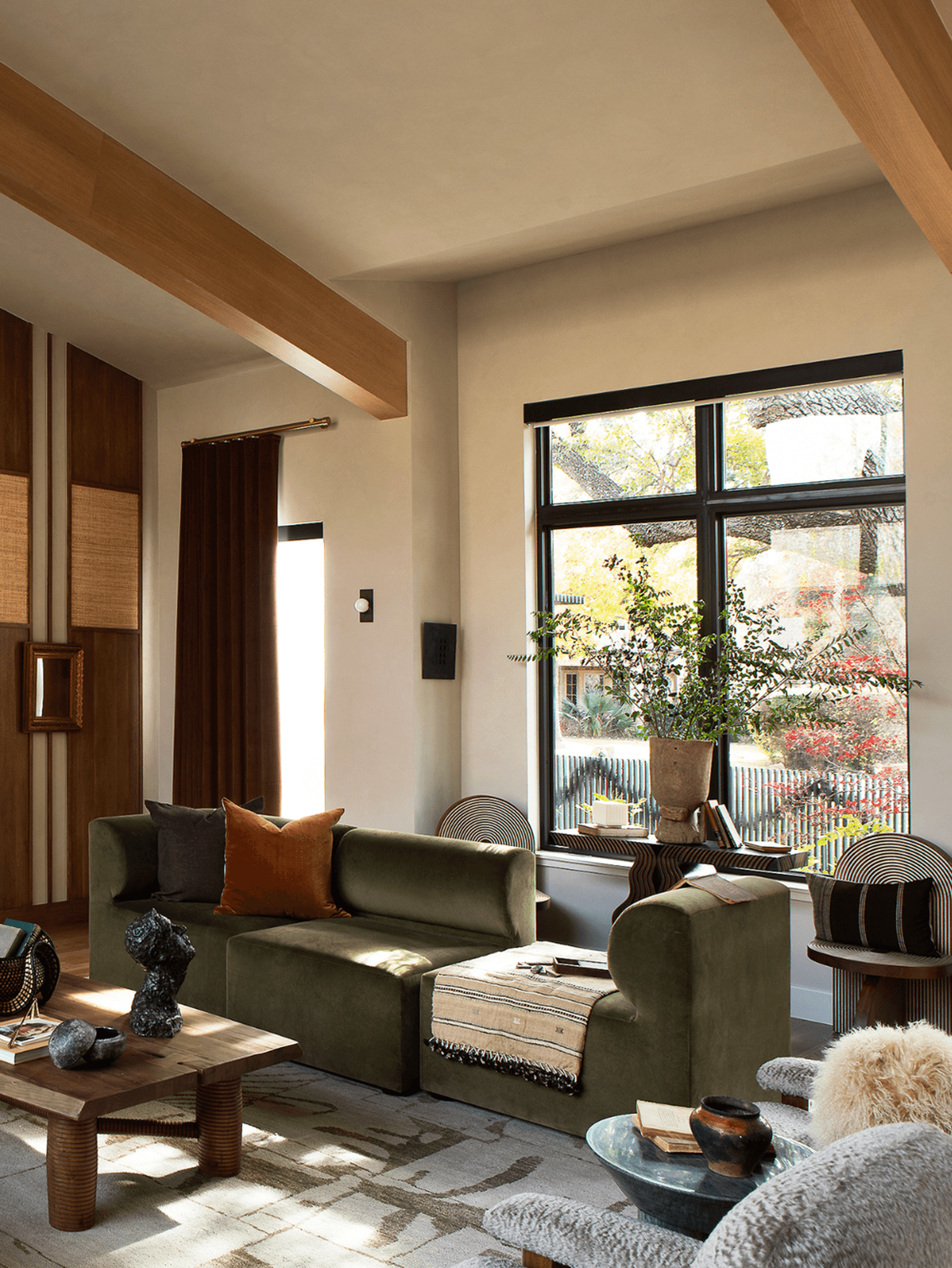 Cozy modern living room with green sofas, wood accents, and a large window.