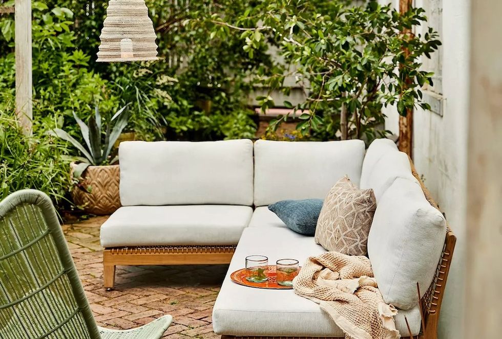 Cozy outdoor patio with white sectional, plants, and woven lanterns.