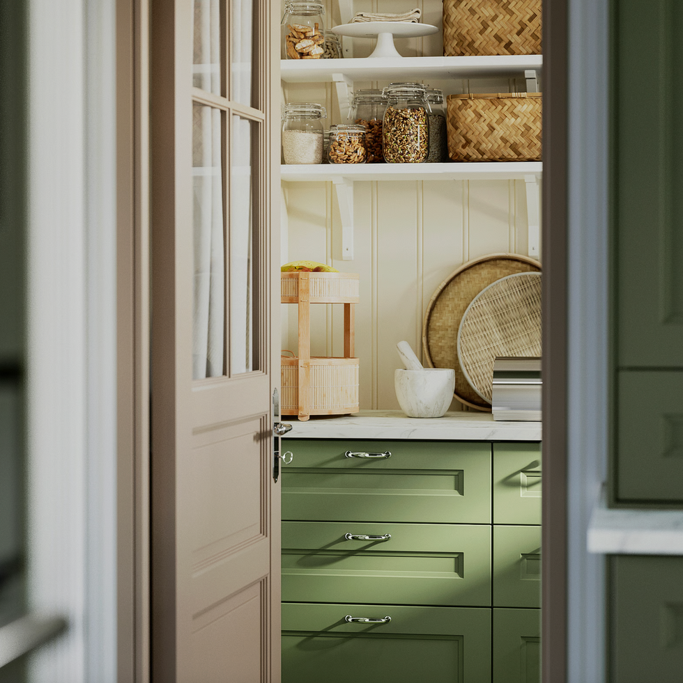 Cozy pantry with green cabinets, jars, woven baskets, and countertop decor.