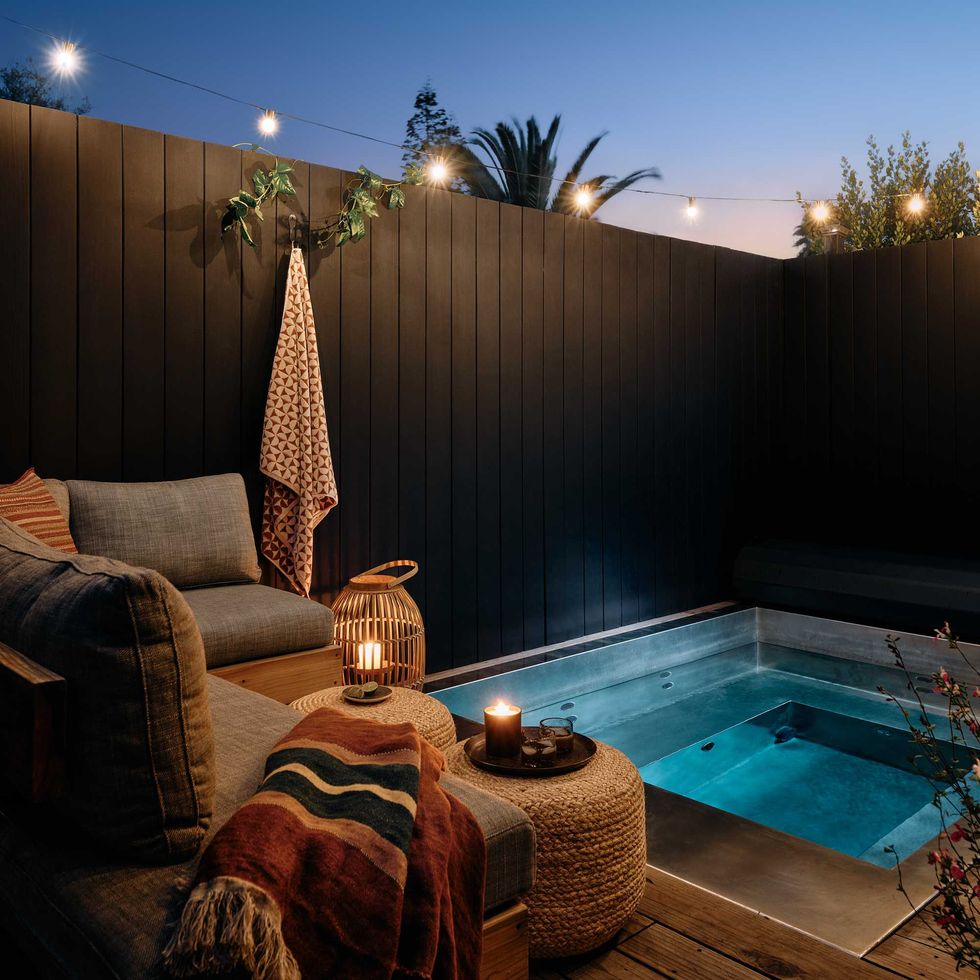 Cozy patio with a hot tub, lanterns, and string lights at dusk.