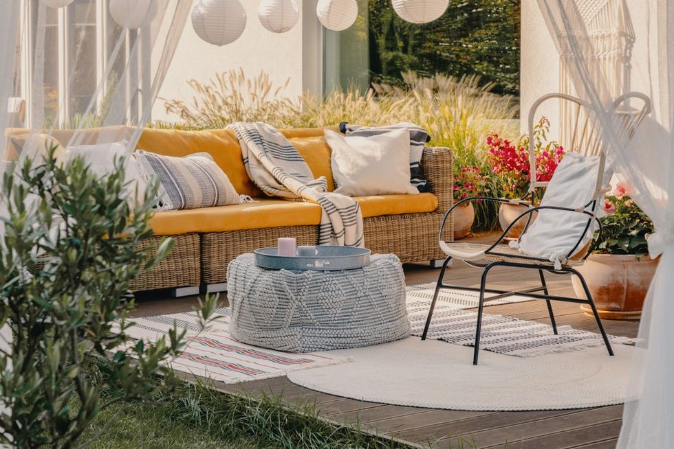 Cozy patio with a yellow sofa, decorative pillows, and a round woven coffee table