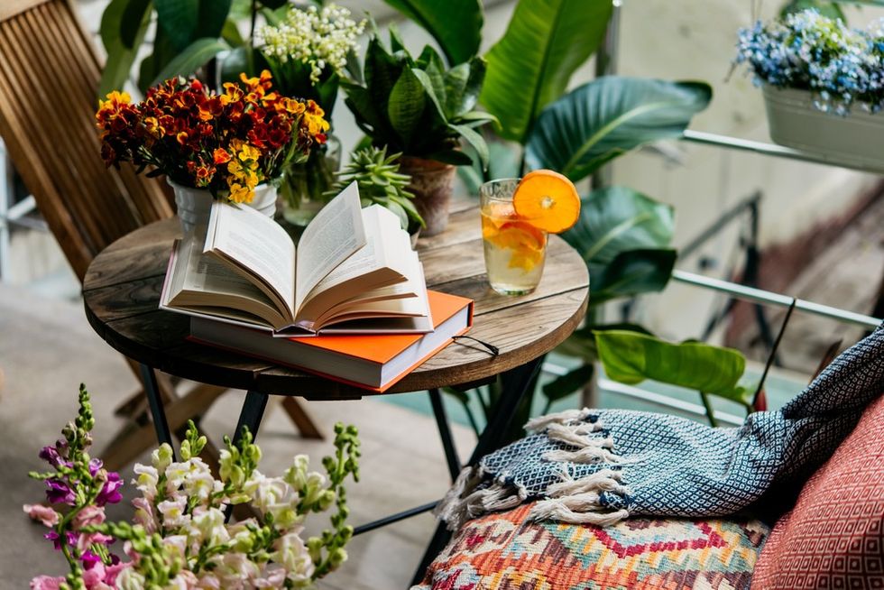 Cozy patio with plants, open book, and a glass of citrus beverage on a wooden table