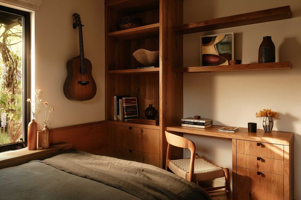 Cozy room with wooden decor, guitar on wall, desk, and bookshelves.