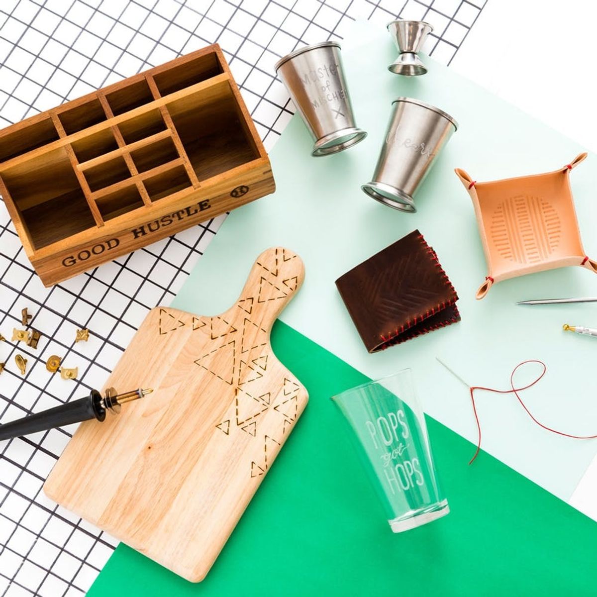 Craft tools and supplies on a grid surface with green and mint papers.