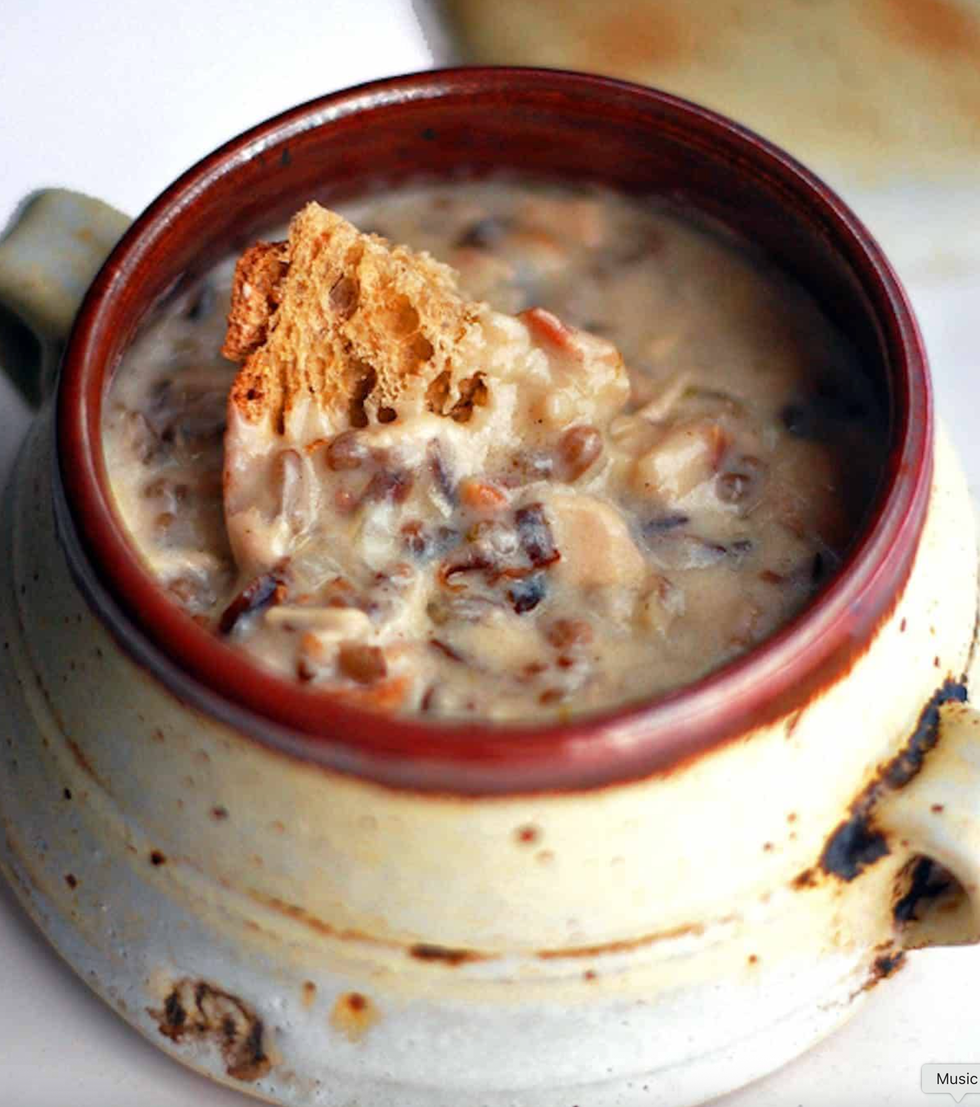 Creamy soup with a bread chunk in a rustic ceramic mug.
