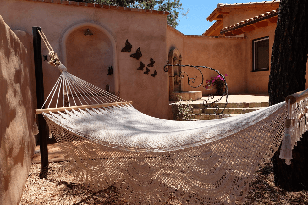 Crocheted hammock in a sunny courtyard with butterfly wall art.