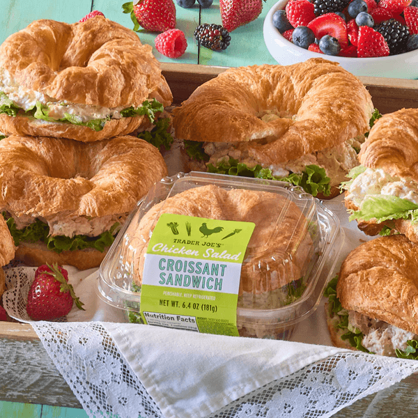 Croissant sandwiches with lettuce and chicken salad, surrounded by fresh berries.