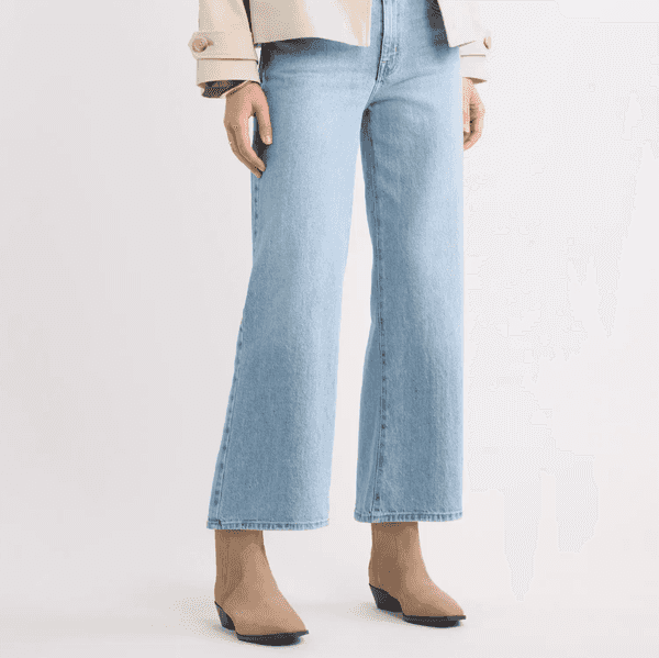 Cropped view of a model wearing light-wash wide-leg jeans and beige ankle boots.