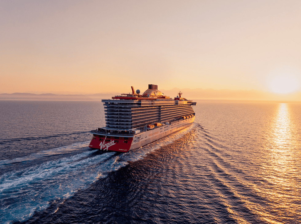 Cruise ship at sea during sunrise, creating a serene golden reflection on the water.