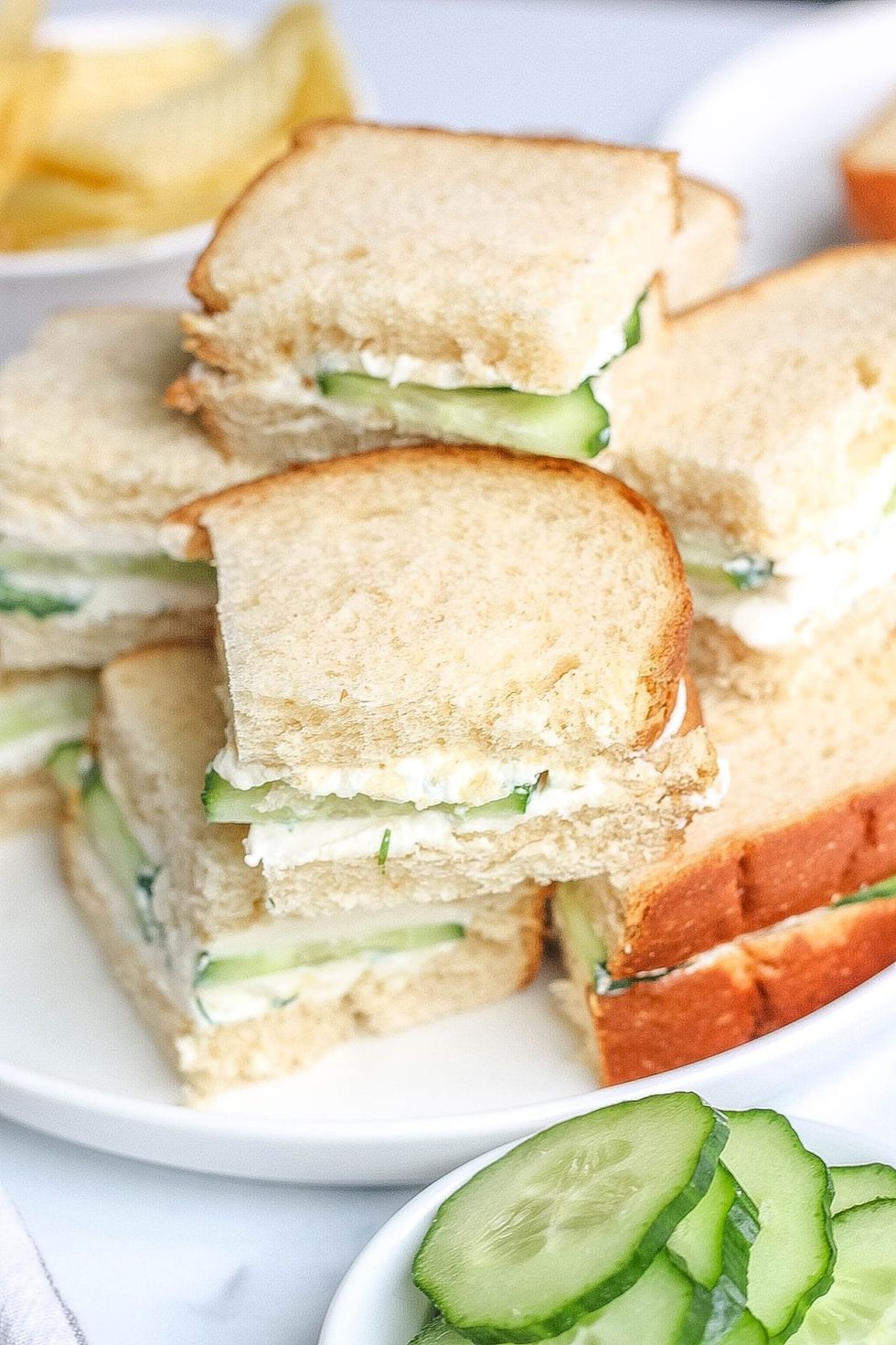 Cucumber sandwiches are stacked on a plate.