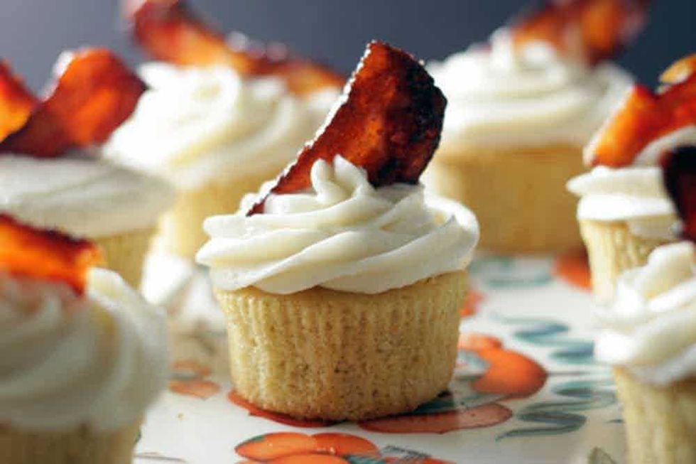 Cupcakes with white frosting topped with crispy bacon strips.