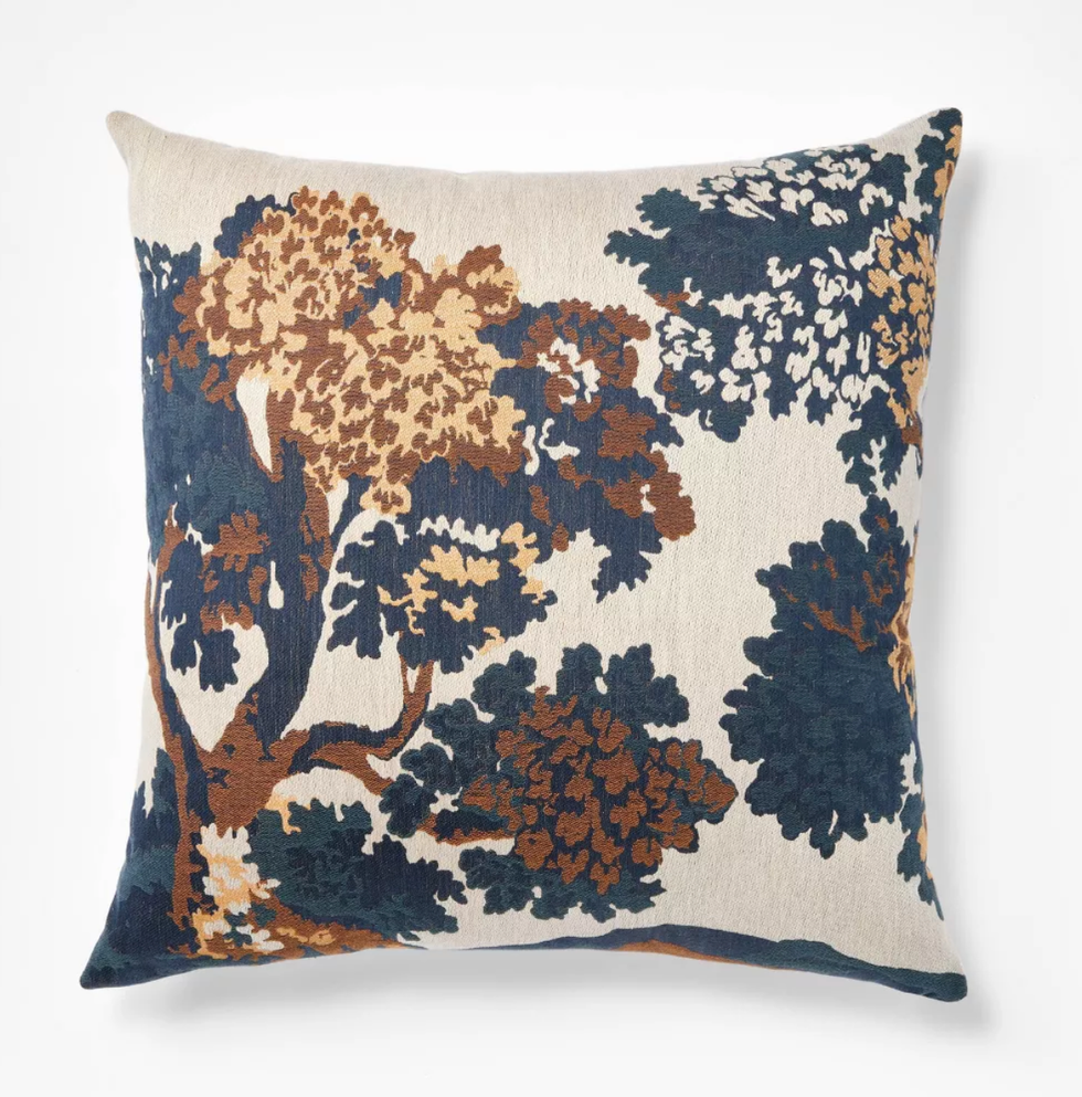 Cushion with abstract tree pattern in navy, brown, and tan on a beige background.