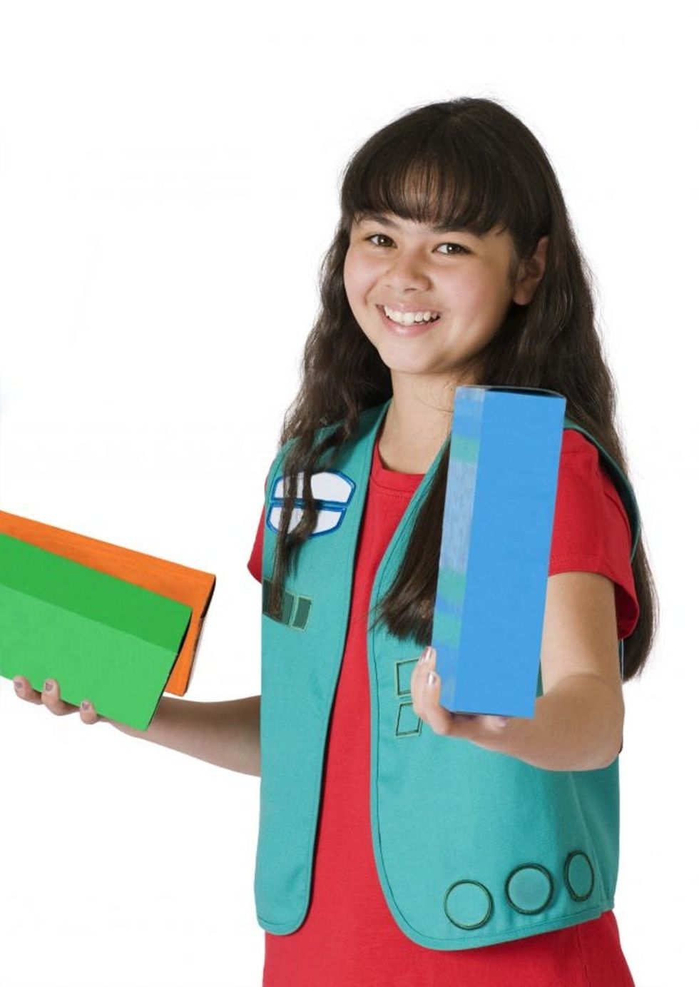 Cute young girl scout offering boxes of girl scout cookies. Suggestive of girl scout or other organized youth group selling cookies or candy as a fundraiser. Isolated on white.