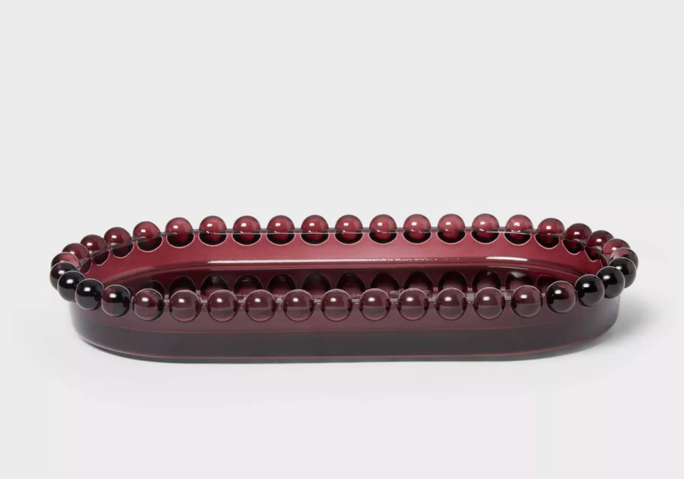 Dark red decorative glass tray with beaded rim on a white background.