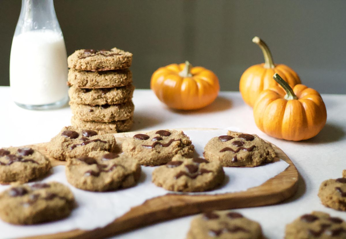 Decorated Paleo Halloween Pumpkin chocolate chip Cookies on a tray with small pumpkins