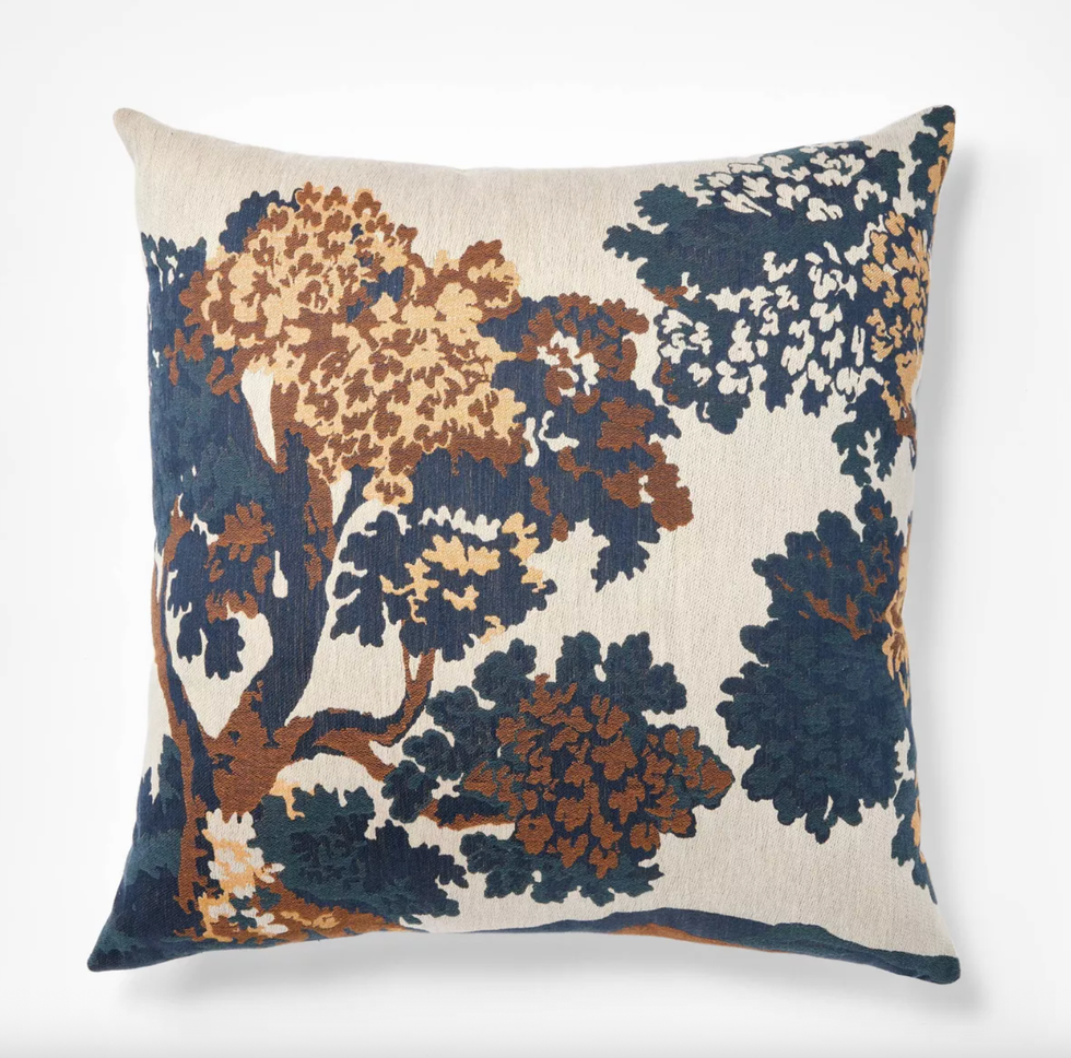 Decorative pillow with blue and brown floral tree pattern on beige background.