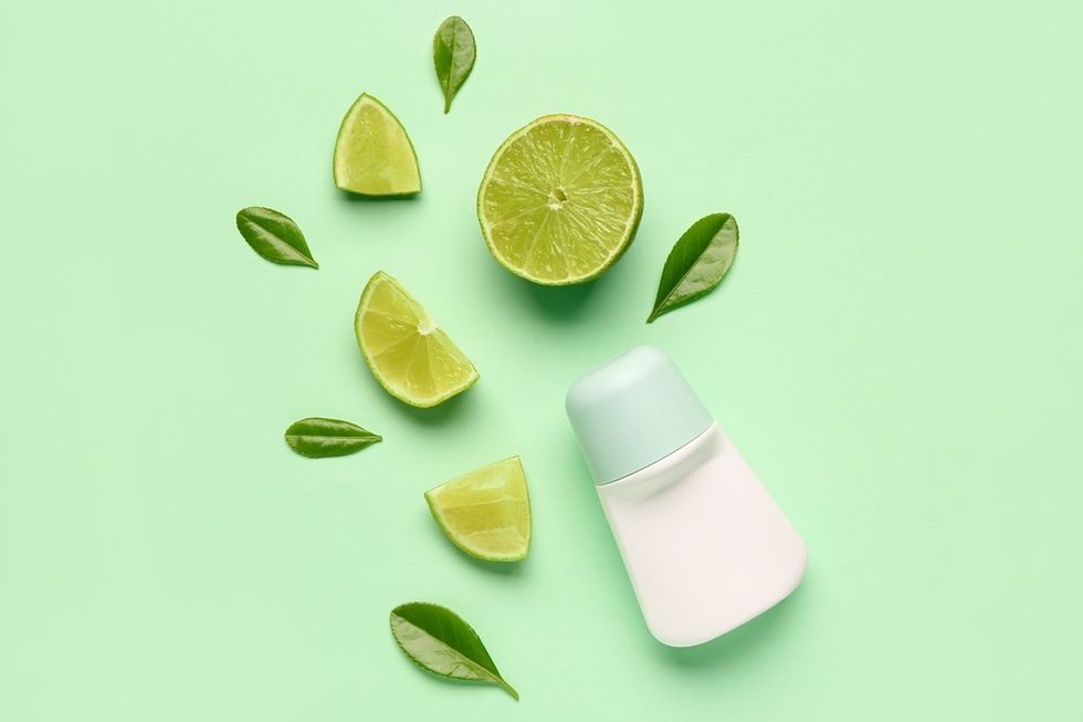 Deodorant with lime slices and green leaves on a light green background.