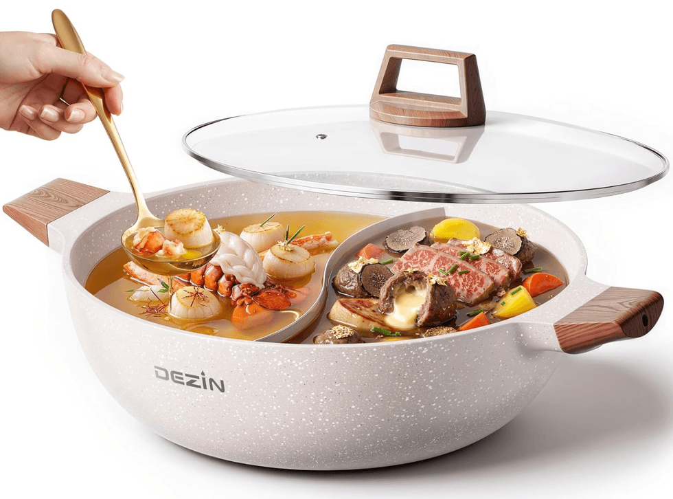 Divided pot with seafood soup and steak stew, garnished, with a hand holding a ladle.