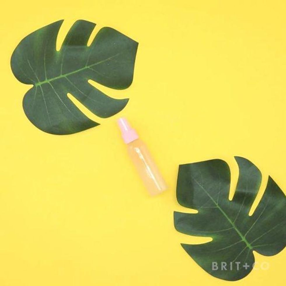 diy sea salt spray in a pink bottle on a yellow background surrounded by palm leaves