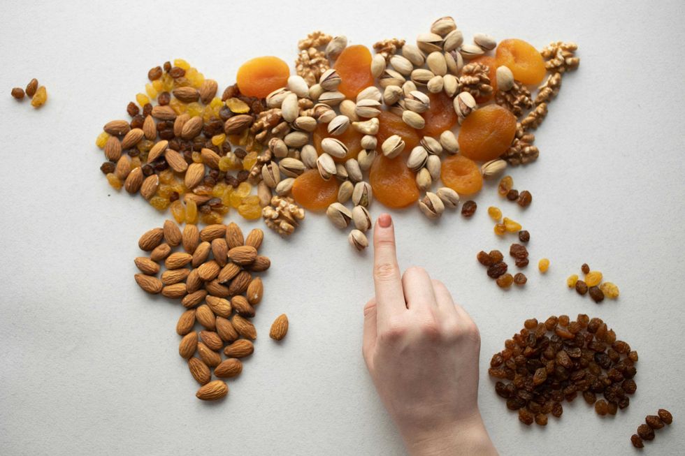 Dry fruits arranged as a world map, with a hand pointing at Africa.