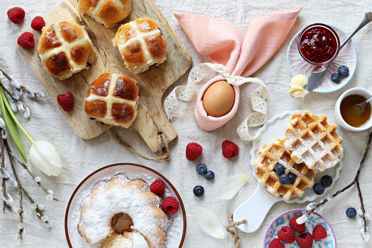 Easter brunch spread with hot cross buns, waffles, berries, and pastel decorations.