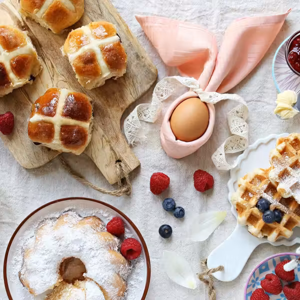 Easter brunch spread with hot cross buns, waffles, berries, and pastel decorations.