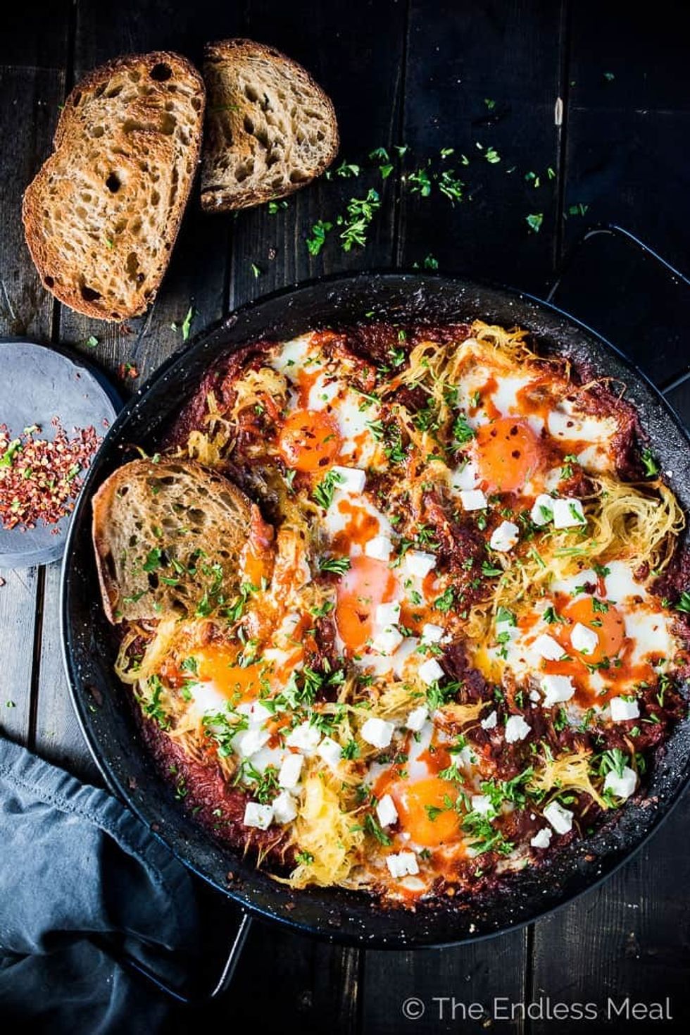 Eggs in purgatory are in a pan on a black surface.