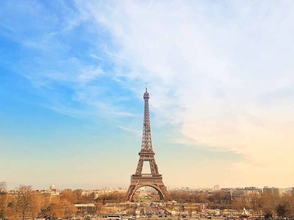 Eiffel Tower under a clear blue sky in Paris, surrounded by cityscape and bare trees.