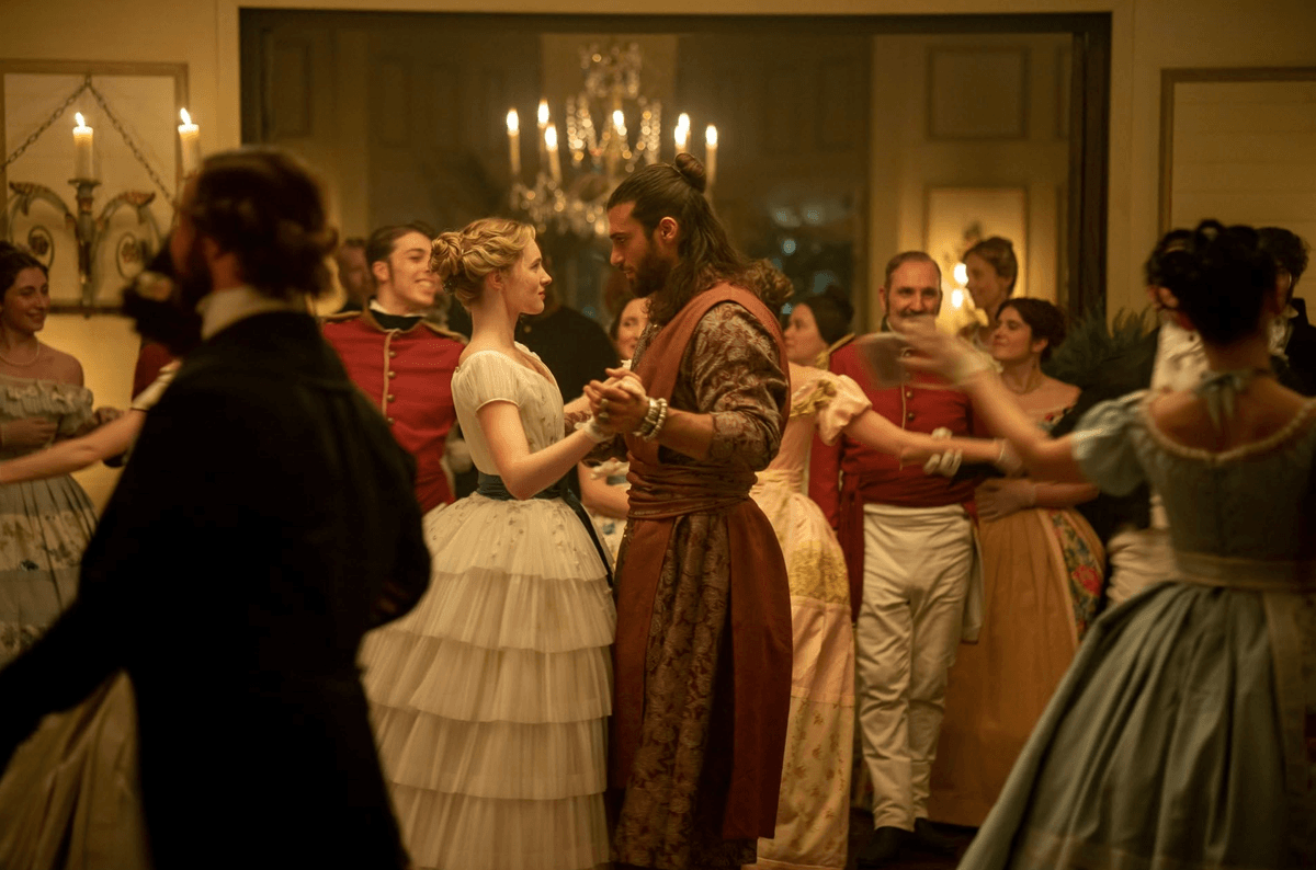 Elegant ballroom dance with couples in historical attire, under a chandelier's glow.