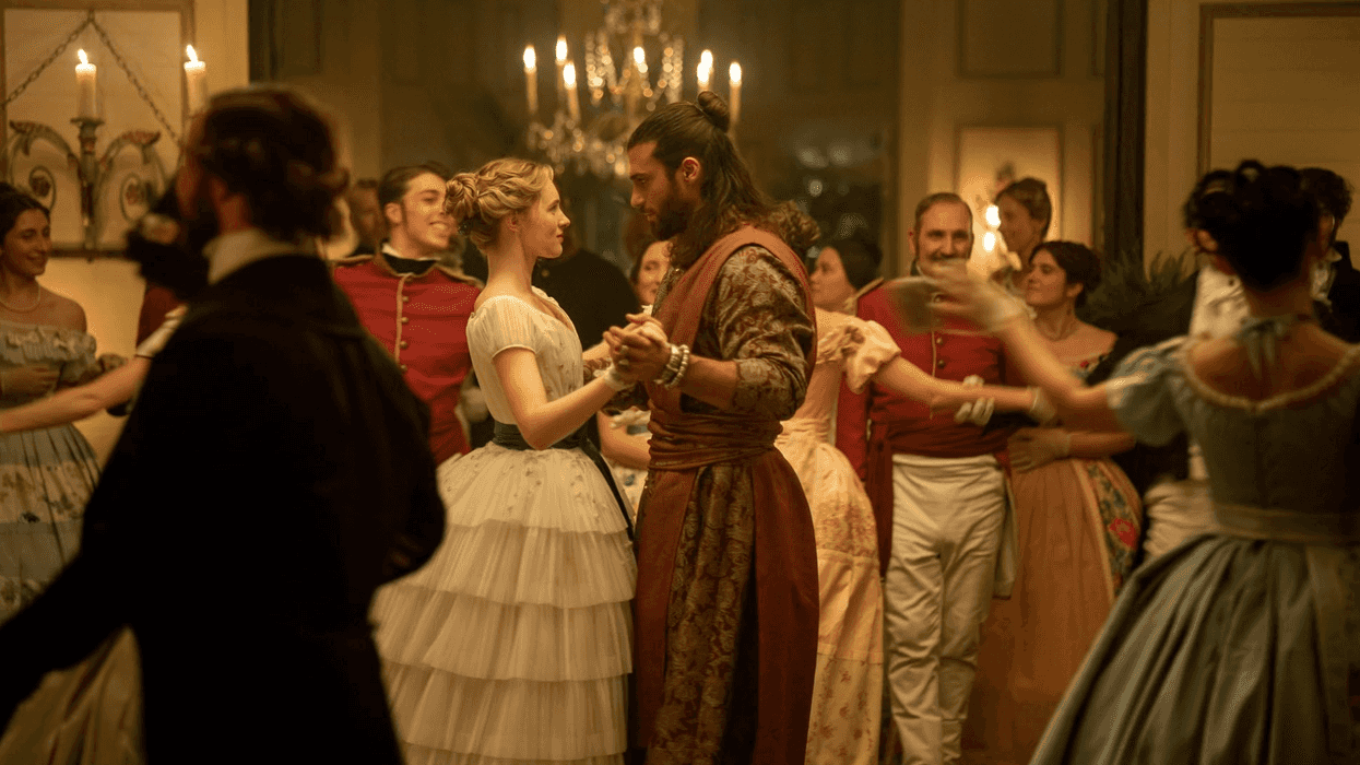 Elegant ballroom dance with couples in historical attire, under a chandelier's glow.