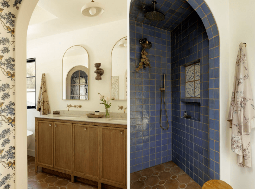Elegant bathroom with blue tiled shower and wooden vanity under arched ceilings.