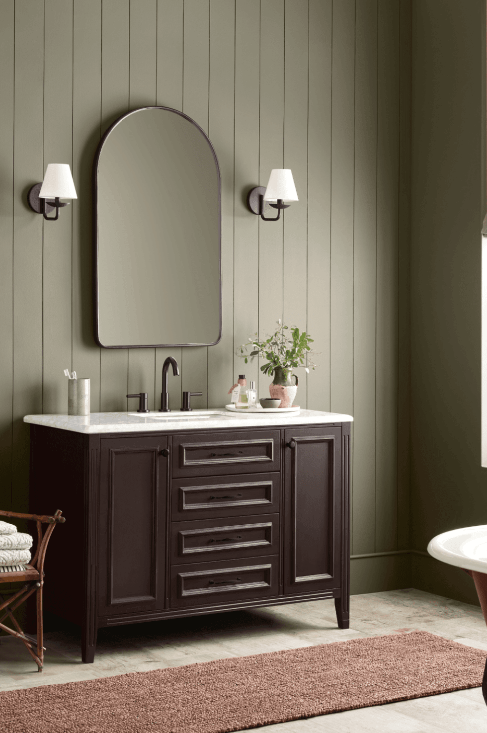 Elegant bathroom with dark vanity, large mirror, and wall sconces.