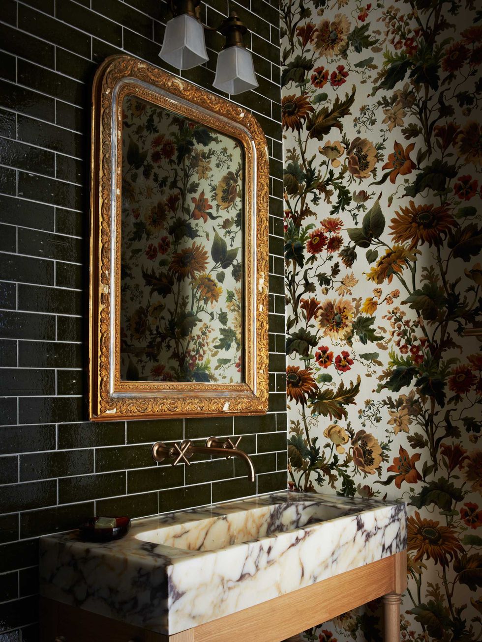 Elegant bathroom with floral wallpaper, ornate mirror, and marble sink.