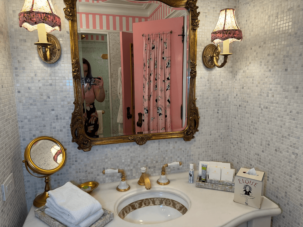 Elegant bathroom with gold accents, ornate mirror, and patterned pink curtain.