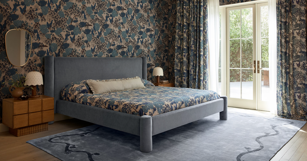 Elegant bedroom with floral wallpaper, matching bedding, and a large window with curtains.