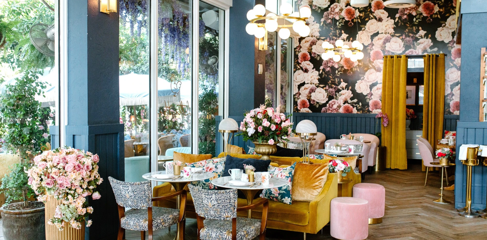 Elegant cafe with floral decor, velvet seating, and ambient lighting.