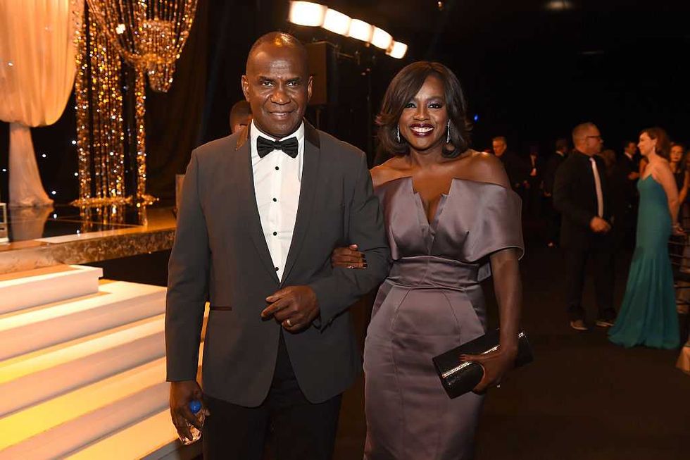 Elegant couple posing at a formal event with glamorous decor.