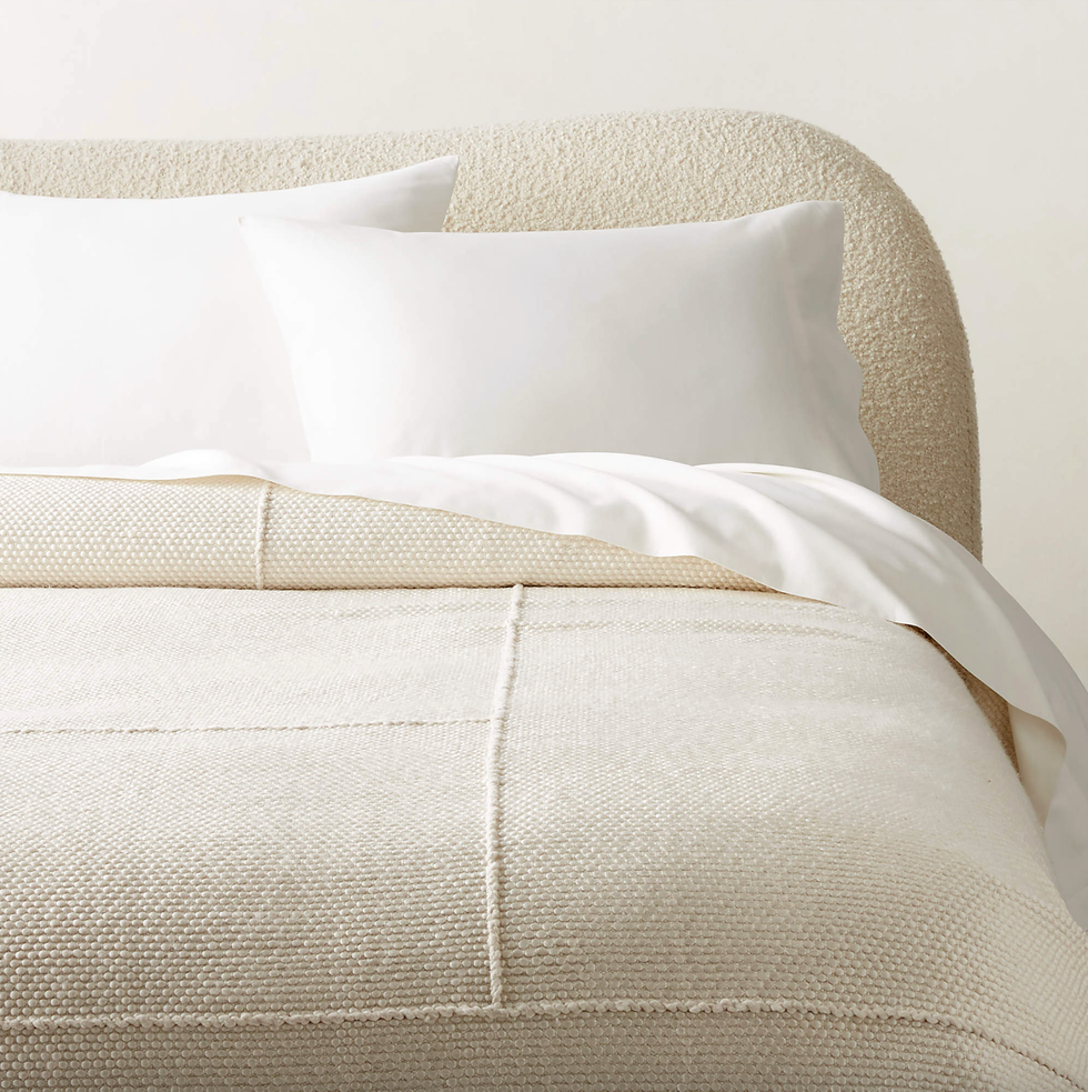 Elegant, cream-colored bed with textured comforter and white pillows.