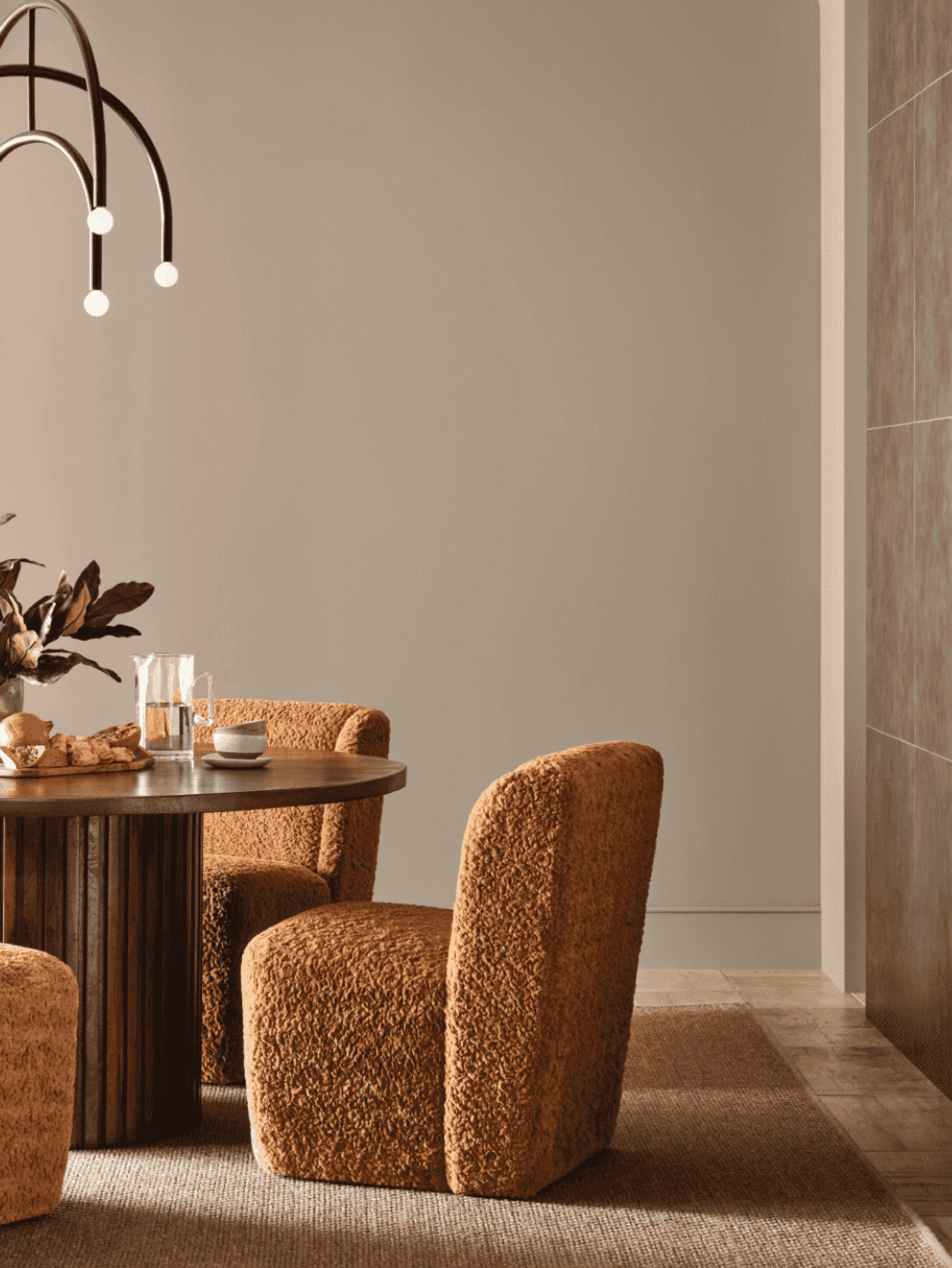 Elegant dining area with a round table, textured chairs, and modern pendant light.